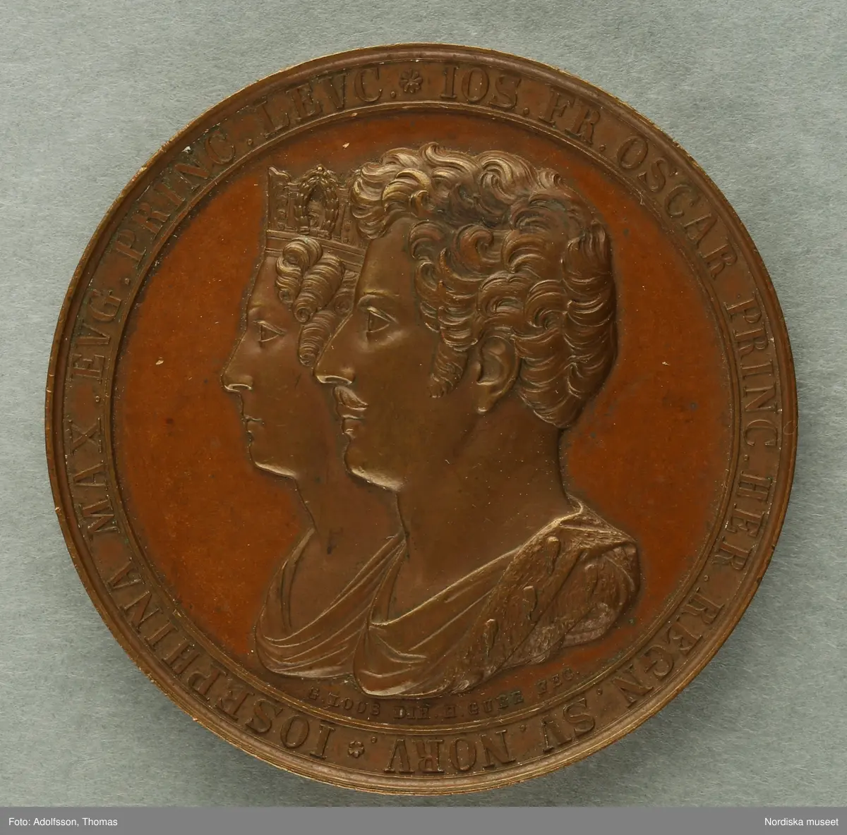 Huvudliggaren.
"2 minnespenningar.
a) I brons. Karl XIV Johan uppstigen på Sveriges och Noriges troner 5/5 1818. Åtsidan Carl XIII och Carl XIV Johans bröstbilder vända mot hvarandra, jmfr. Hildebrand, B. E. 'Sveriges och svenska konungahusets minnespenningar, praktmynt och belöningsmedaljer' del 2, sid 335, nr 22.
b) I brons. Kronprins Oscars förmälning med prinsessan Josefine af Leuchtenberg, i Stockholm den 19 juni 1823. Åtsidan: kronprinsens och kronprinsessans brösbilder förenade. Jmfr. Hildebrand, B. E. 'Sveriges och svenska konungahusets minnespenningar, praktmynt och belöningsmedaljer' del 2, sid 405 nr 7.
G. löjtnant C. V. E. Ridderstad 13/12 1876."