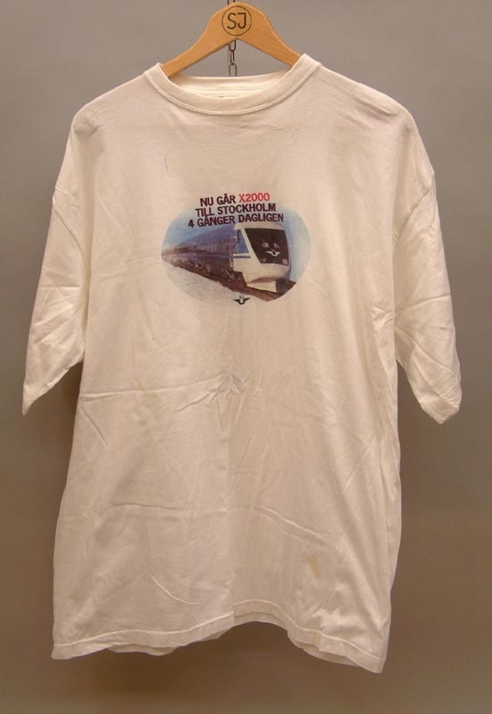 Vit t-shirt med text "Nu går X2000 till Stockholm 4 gånger dagligen."
Bild under av X2000 med en liten svart SJ-logga.
På baksidan en räls med texten Ostkustbanan, Härnösand, Sundsvall, Hudiksvall, Söderhamn, Gävle, Uppsala och Stockholm.
Storlek XL.