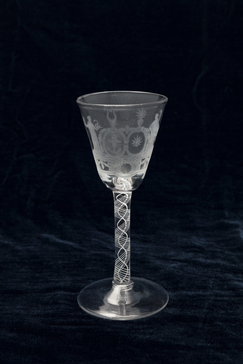Vinglass; høy stett med hvite tråder, cupa traktformet med gravert felt. To gudinner flankerer to skjold, det ene med anker, det andre med Morgenstjernen?