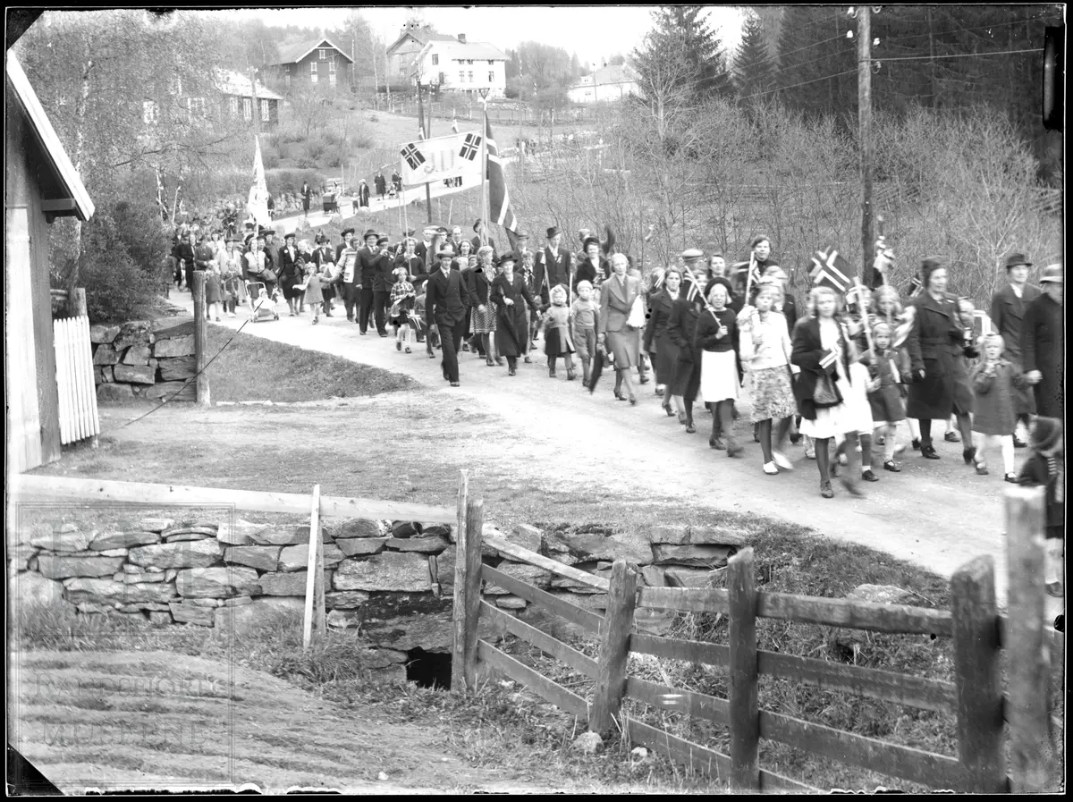 17. mai tog kommer Ålsvegen på Jaren med musikkorps og folk med faner og flagg.