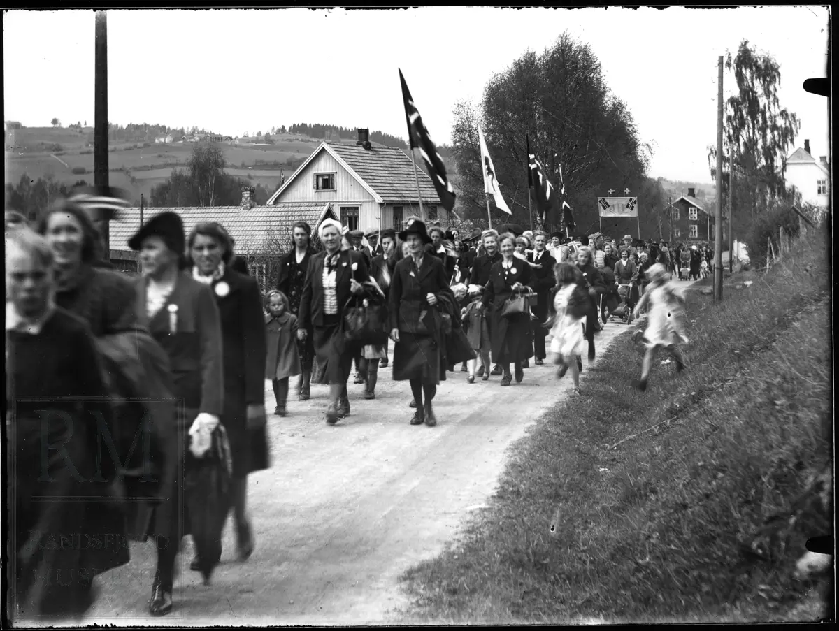 17. mai tog kommer Ålsvegen på Jaren med musikkorps og folk med faner og flagg.