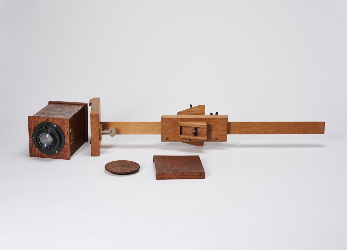 Bokskamera med objektiv, mattskive og stativ (mangler ben og kamera mangler en plateholder). Kamera er bygget av arkitekt Hans Grendahl (1877-1957). 
Objektivet er et Carl Zeiss Jena Tessar 1:45 F=18cm DRP.