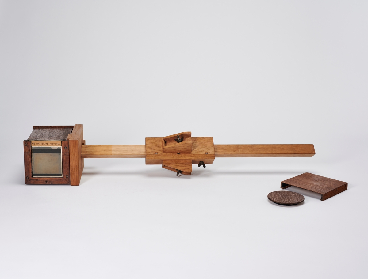 Bokskamera med objektiv, mattskive og stativ (mangler ben og kamera mangler en plateholder). Kamera er bygget av arkitekt Hans Grendahl (1877-1957). 
Objektivet er et Carl Zeiss Jena Tessar 1:45 F=18cm DRP.