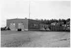 Vägstation B7, Åkersberga. Huvudbyggnad med från vänster verkstad, kontorsdel och garagedel. Personbilar Ford Taunus och Volvo PV parkerade framför kontorsdelen.