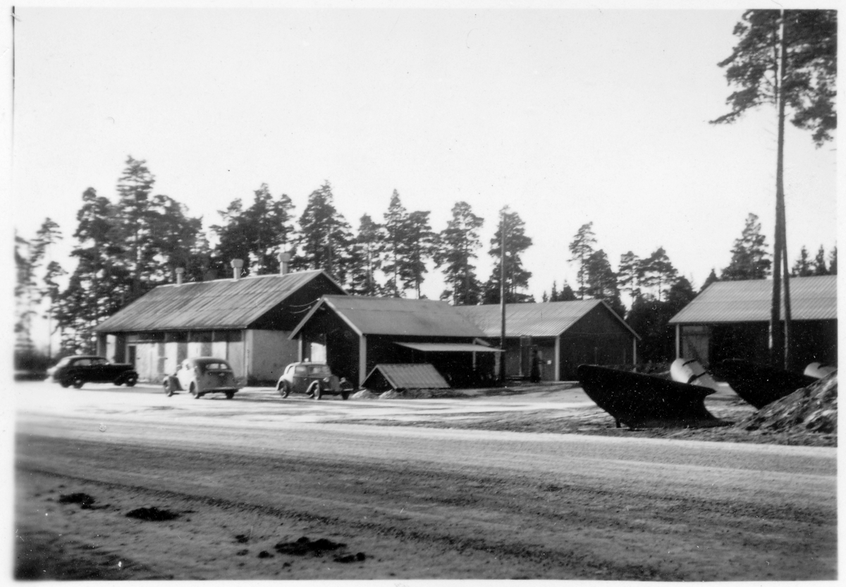 Vägstation C4, Björklinge. Garagebyggnad invid väg. Personbilar framför garaget. Spetsplogar.