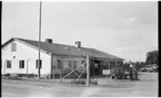 Vägstation D5, Flen. Vägstationens huvudbyggnad med kontorsdel till vänster och garagedel till höger. Bensinpump (drivmedelspump), Volvo Duett framför bensinpumpen. Skylt med texten 