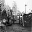 Vägstation E13, Stjärnvik. Bakgård, nätgrind vid byggnad, diverse materialupplag.