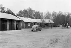 Vägstation N2, Skedala. Garage- och förrådsbyggnader. Sten- och stubbrytare uppställd. Bensinpumpar (drivmedelspumpar). På garageplan personbil Volvo PV, N8788, med skylten 