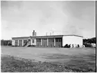 Vägstation N6, Varberg. Vägstationens huvudbyggnad med (från vänster) verkstad, kontor, garage. Upplag av cementrör vid gaveln. Spetsplog skymtar till höger.