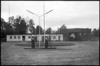 Vägstation P4, Tranemo. Vägstationens huvudbyggnad, med kontor, förråd och verkstad. I förgrunden bensinpumpar (drivmedelspumpar). Framför byggnaden personbil Saab.