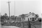 Vägstation P15, Tösse, filial Mellerud. Vägstationens huvudbyggnad med från vänster garage, kontor, verkstad. Ingång till verkstaden på gaveln. Bortanför denna byggnad kombinerad förråds- och garagebyggnad, samt ytterligare en förrådsbyggnad. Bensinpumpar (drivmedelspumpar) personbil framför bensinpumpen. Flaggstång på garageplan. Nätstängsel med kraftiga trästolpar.