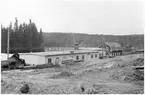 Vägstation P16, Bengtsfors. Vägstationens huvudbyggnad med verkstad, kontor och garage (baksidan). Markberedning pågår. Decauvillevagnar. Bortom denna byggnad äldre byggnad med skylt på framsidan 