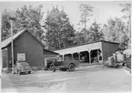 Vägstation R6, Ullervad. Förrådsbyggnader, ett öppet skjul. Framför byggnaden en sand- och gruskärra, motor på underlag  med järnhjul, personbil Volvo PV R14021 med skylten 