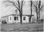 Vägstation T3, Hallsberg. Garage och kontorsbyggnad. Kontorsdelen i främre delen av byggnaden. Personbil Volvo PV, T19216, framför byggnaden. Cykelställ med cyklar, flaggstång.