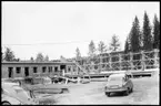 Vägstation Y1, Ånge. Byggande av ny vägstation. Kontors- och förrådsbyggnad. Personbilar i förgrunden, Saab B79415 och Volkswagen.