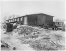 Depåförrådet i Älandsbro (Vägstation Y6). Förrådsbyggnad. Upplag av diverse material utanför byggnaden.
