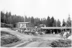 Vägstation Y11, Nyland. Förrådsbyggnader. Upplag av diverse material, virke. I bakgrunden lastbil under presenning, manskapsvagn ÅSA transportabla manskapsbod, Åmåls Sågverks AB, 1940-talet.