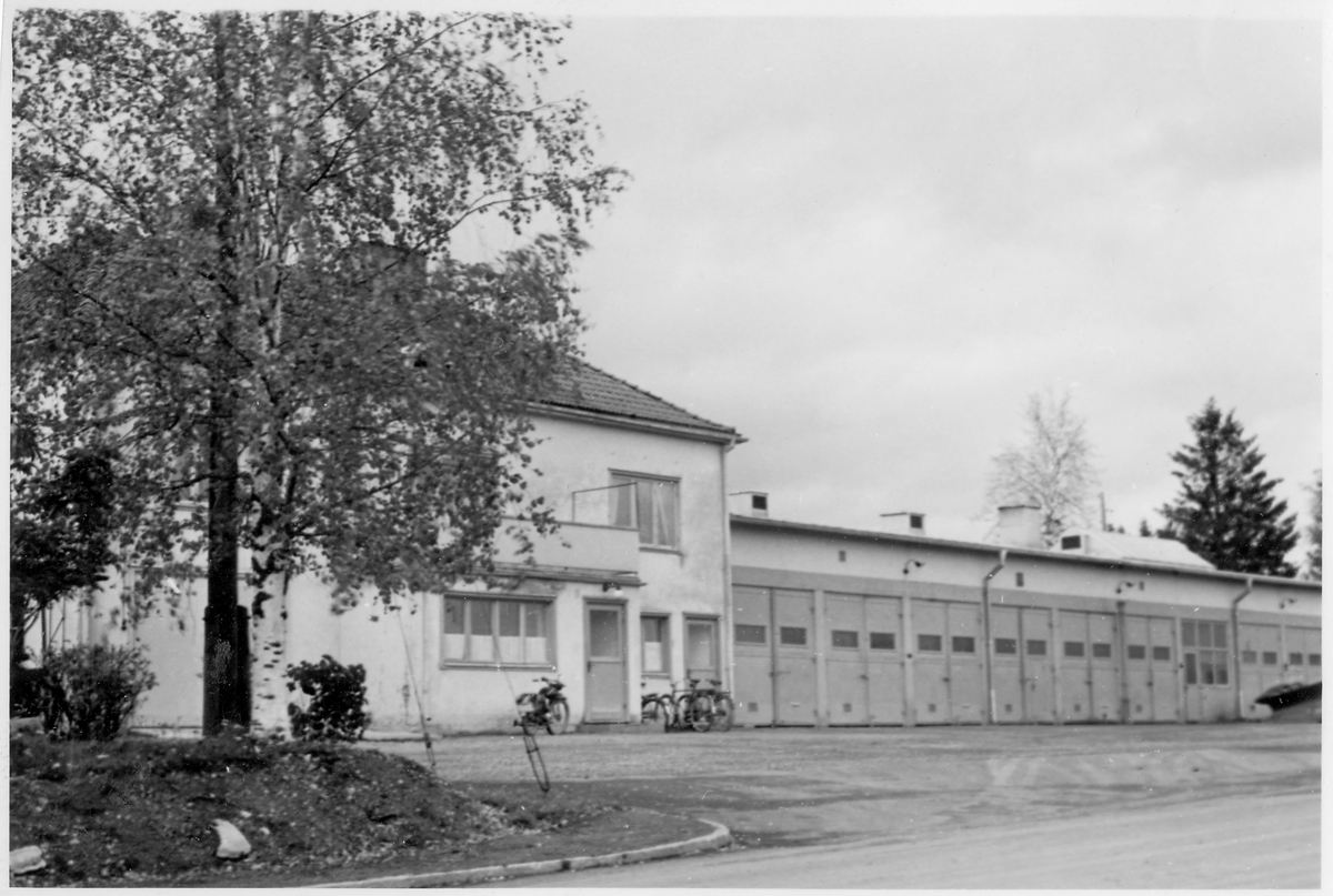 Vägstation Z10, Lit. Garagebyggnad, hopbyggd med bostadshus i två våningar. Spetsplog till höger. Cyklar invid bostadshus. Invid väg.
