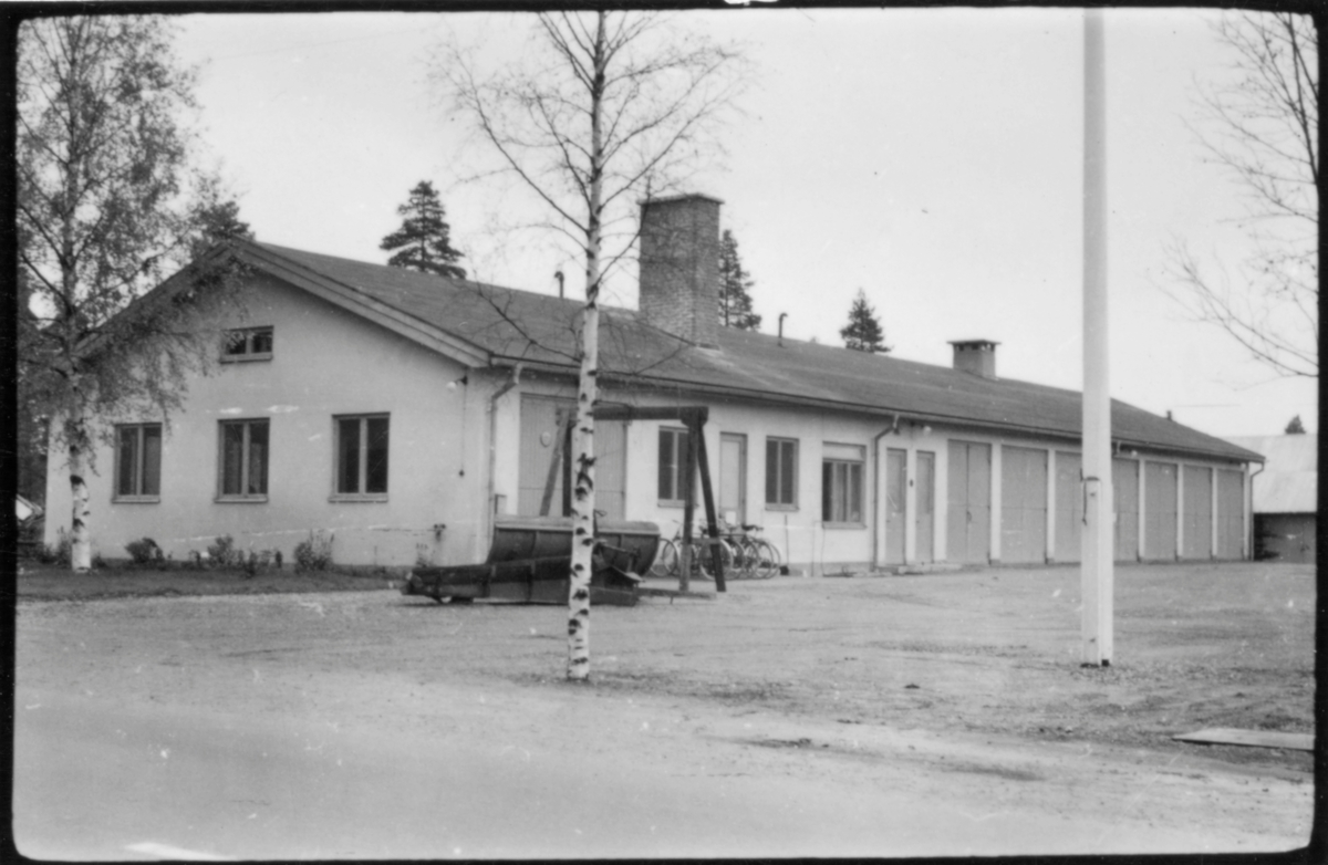 Vägstation AC1, Nordmaling. Vägstationens huvudbyggnad med (från vänster) verkstad, kontor och garage. Snöplogar framför verkstaden. Flaggstång på garageplan. Cykelställ med cyklar.