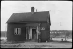 Vägstation AC9, Skellefteå, färjvaktarbostad Örviken. Bostadshus för färjvaktaren. Cyklar vid huset. Vattenbrunn. Färjleden och färjeläge skymtar i bakgrunden.