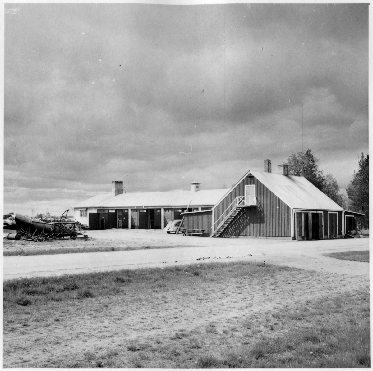 Vägstation BD3, Gammelstaden. Vy mot vägstationen med kontors- och garagebyggnaden i bakgrunden. Förrådsbyggnad till höger. Sidoplog på planen framför byggnaden, personbil.