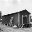 Vägstation BD8, Överkalix. Förrådsbyggnad med lastkaj. Stolpar till vägmärken lutade mot byggnaden.