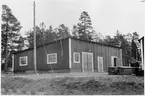 Byggnadsförrådet i VFBD (Vägstation VFBD7, Kalix). Förrådsbyggnad. Framför byggnaden redskapslådor.