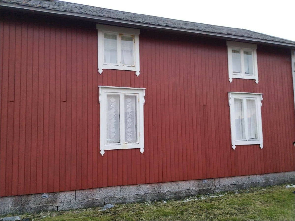 Huset har panel stående panel, malt rødt med hvit dekor på og rundt vinduer. Skifertak.