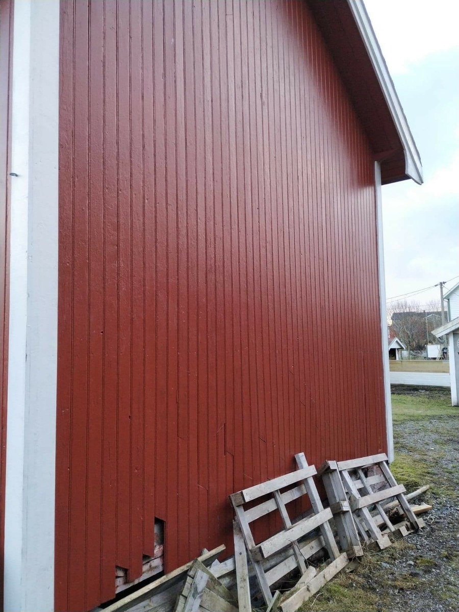 Huset har panel stående panel, malt rødt med hvit dekor på og rundt vinduer. Skifertak.