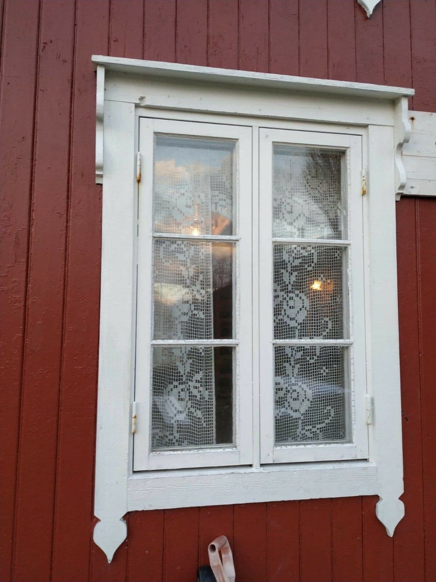 Huset har panel stående panel, malt rødt med hvit dekor på og rundt vinduer. Skifertak.