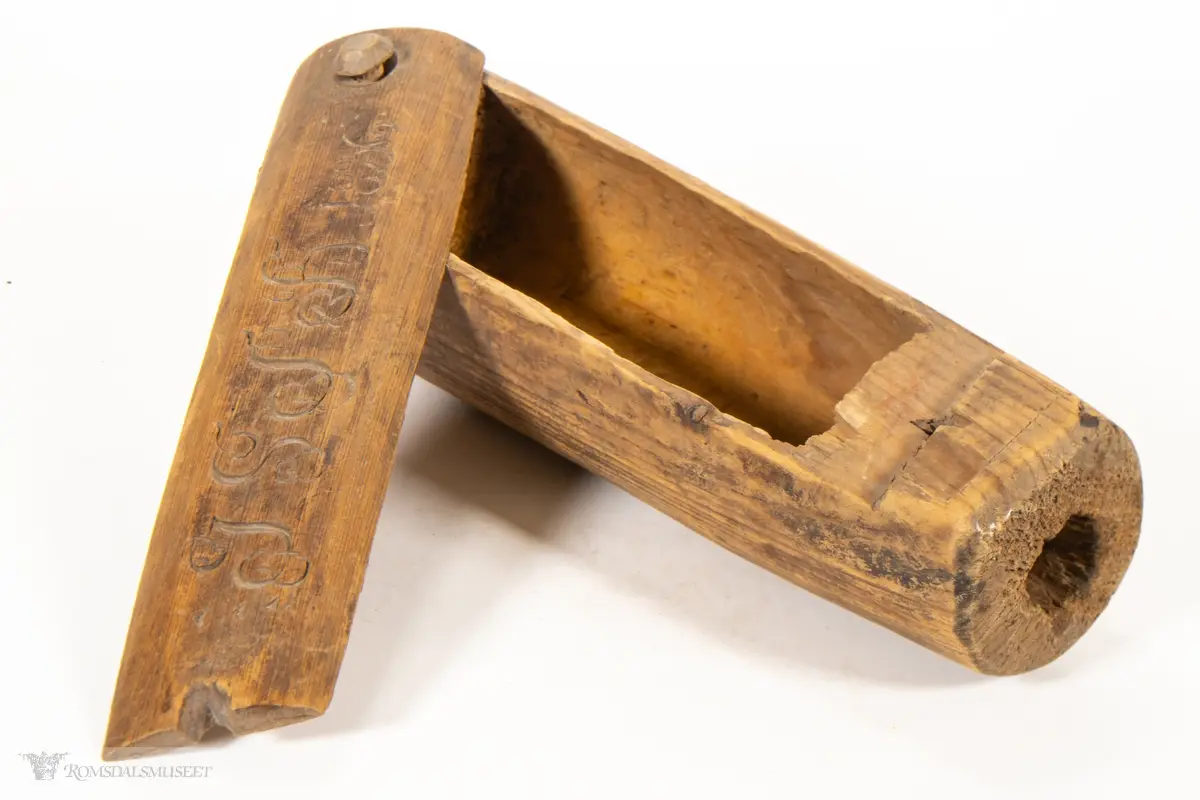 Uthulet stokk med et rom, som smalner av mot enden. Toppen av stokken er skåret av, og skåret til som et dreielokk som dreier om en tretapp. Har en bred, flat base og en uthulet topp, slik at esken kan brukes som en lysestake.