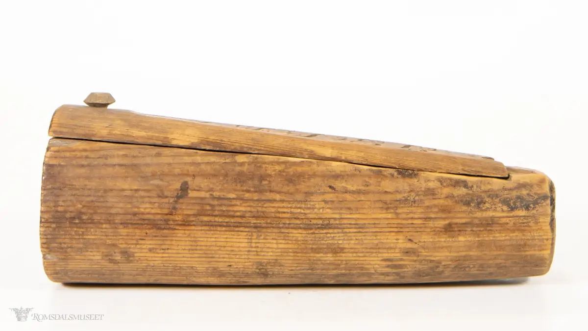 Uthulet stokk med et rom, som smalner av mot enden. Toppen av stokken er skåret av, og skåret til som et dreielokk som dreier om en tretapp. Har en bred, flat base og en uthulet topp, slik at esken kan brukes som en lysestake.