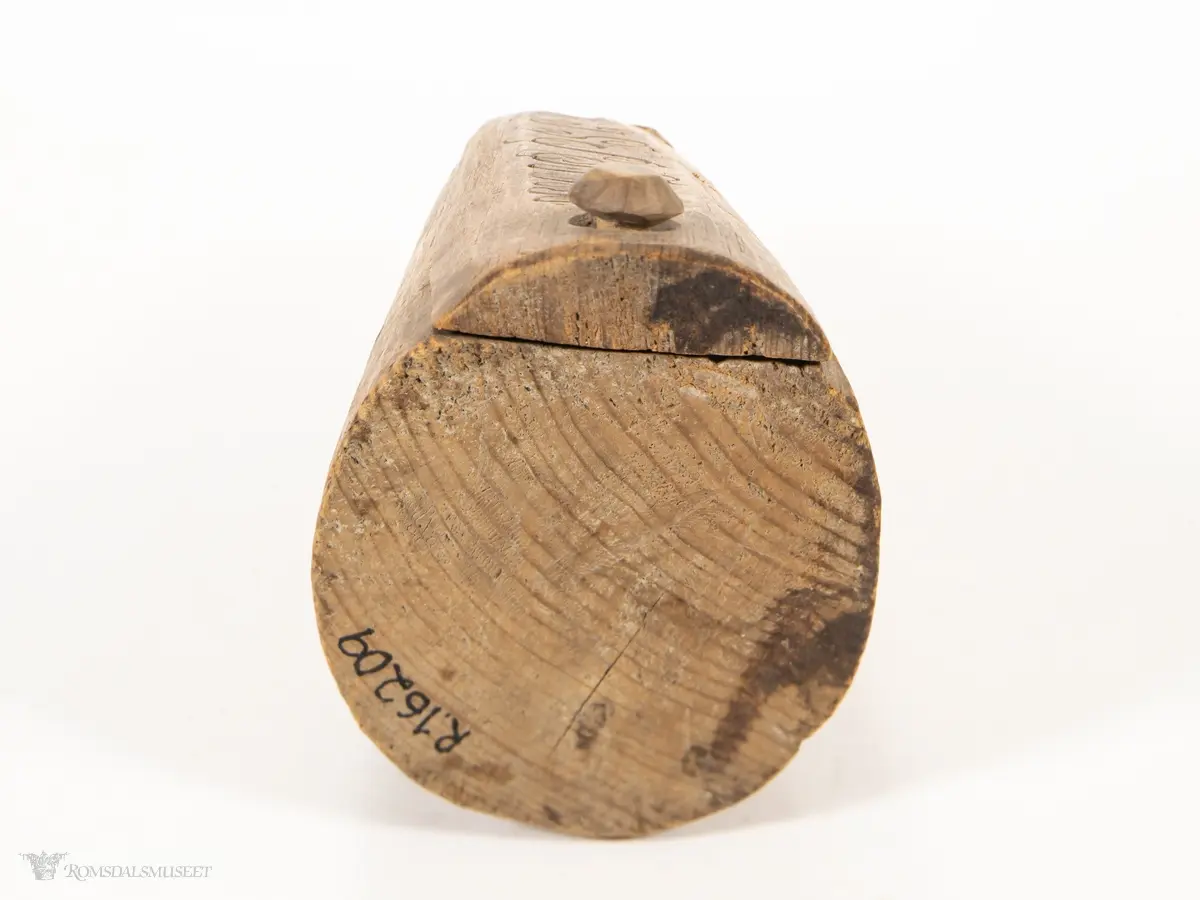 Uthulet stokk med et rom, som smalner av mot enden. Toppen av stokken er skåret av, og skåret til som et dreielokk som dreier om en tretapp. Har en bred, flat base og en uthulet topp, slik at esken kan brukes som en lysestake.