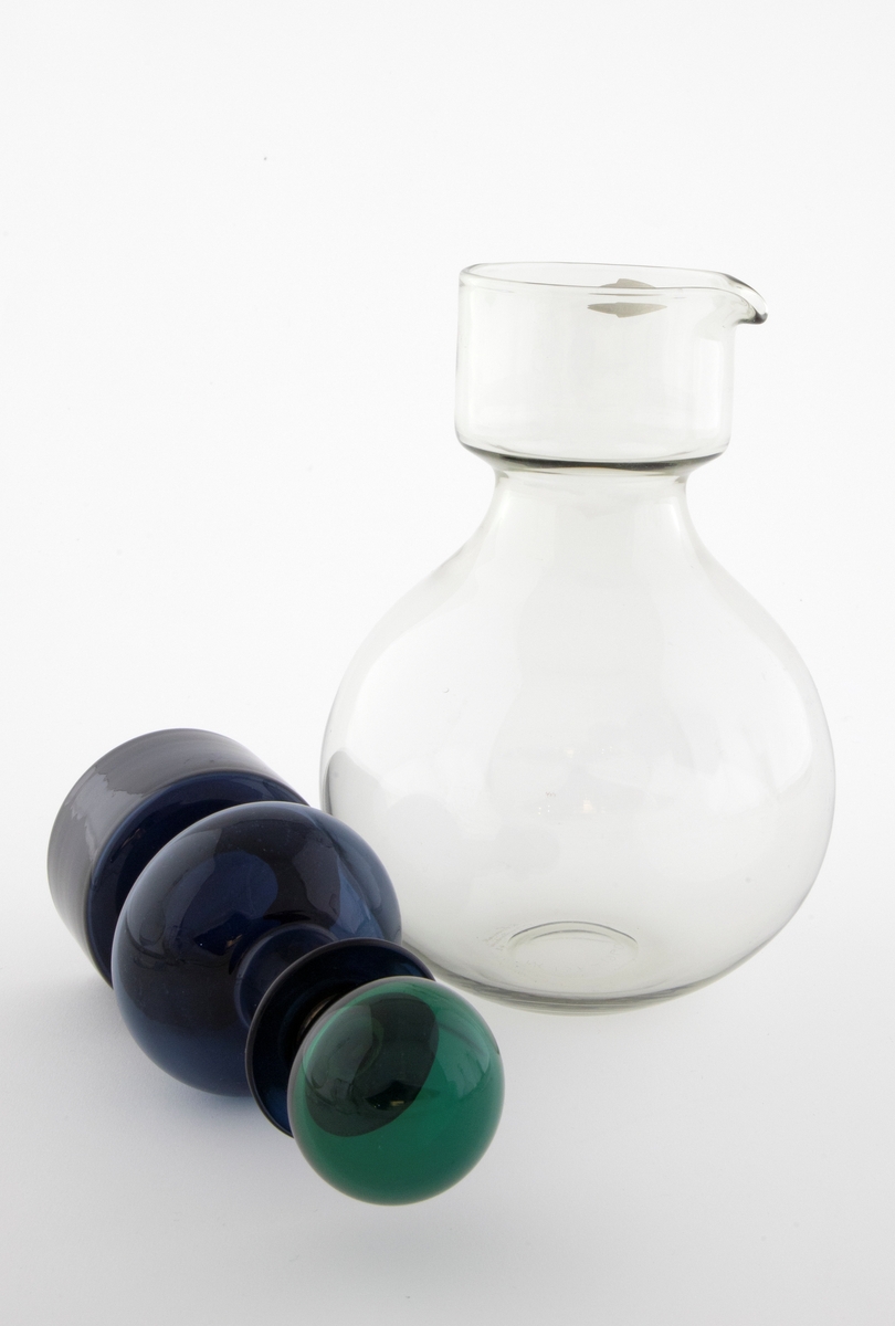 Tredelt karaffel i klart glass: 

1) Stor kuleformet karaffel med hals i klart glass. Sylindrisk hals med tut.
 
2) Mindre karaffel i gjennomskinnelig, blått glass, plassert som propp i den store. Den har kuleformet korpus og sylindrisk hals, og hviler på en sylindrisk fot. 

3) Kuleformet propp plassert i den lille karaffelen, utført i gjennomskinnelig grønt glass og hviler på en korkring.