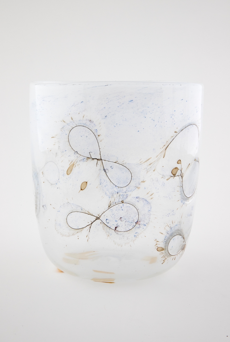 Sylinderformet glassbolle. Bunn og nedre del av korpus er utført i klart glass, mens øvre del domineres av melkehvitt halvgjennomskinnelig glass. Innlagte metalltråder danner åttetalls- og halvsirkelformede elementer på korpus. I glasset er det en rekke luftblærer i ulike størrelser, samt dråpeformede spetter i blått og brunt. Puntemerke under bollens bunn.