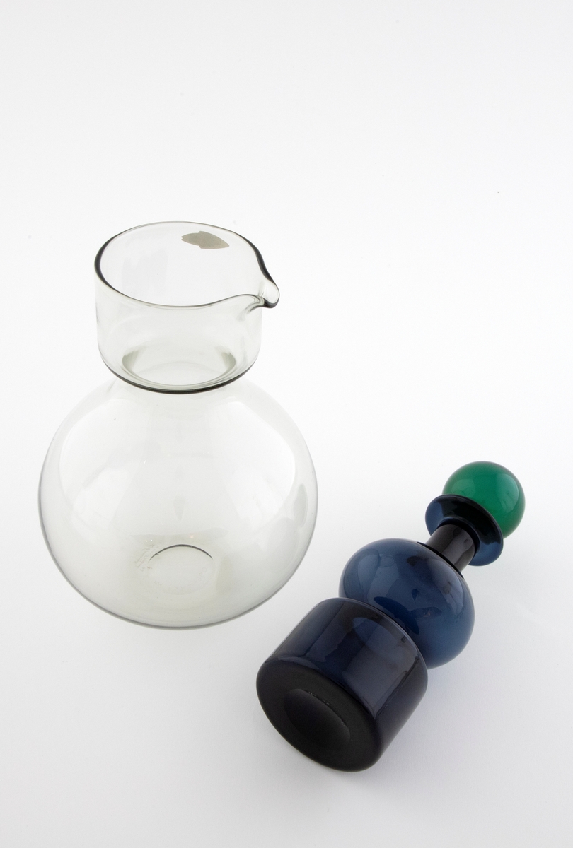 Tredelt karaffel i klart glass: 

1) Stor kuleformet karaffel med hals i klart glass. Sylindrisk hals med tut.
 
2) Mindre karaffel i gjennomskinnelig, blått glass, plassert som propp i den store. Den har kuleformet korpus og sylindrisk hals, og hviler på en sylindrisk fot. 

3) Kuleformet propp plassert i den lille karaffelen, utført i gjennomskinnelig grønt glass og hviler på en korkring.
