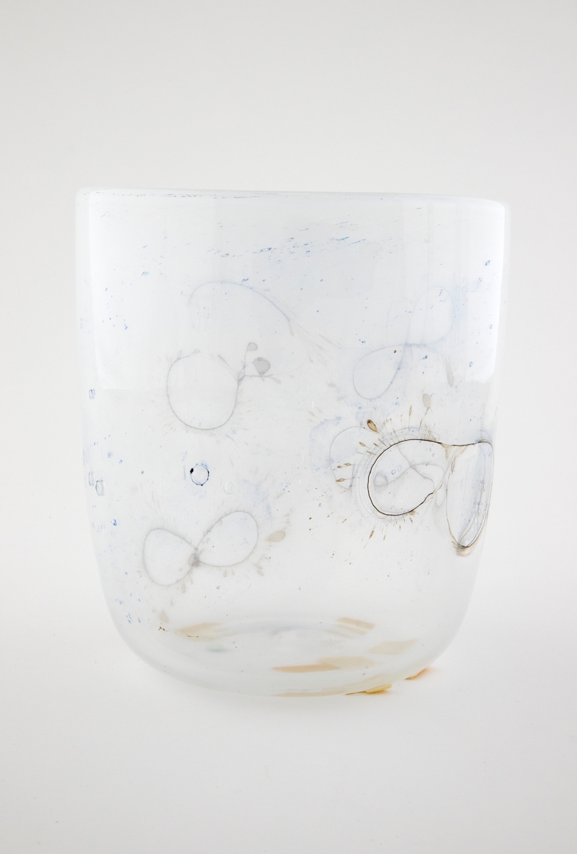 Sylinderformet glassbolle. Bunn og nedre del av korpus er utført i klart glass, mens øvre del domineres av melkehvitt halvgjennomskinnelig glass. Innlagte metalltråder danner åttetalls- og halvsirkelformede elementer på korpus. I glasset er det en rekke luftblærer i ulike størrelser, samt dråpeformede spetter i blått og brunt. Puntemerke under bollens bunn.