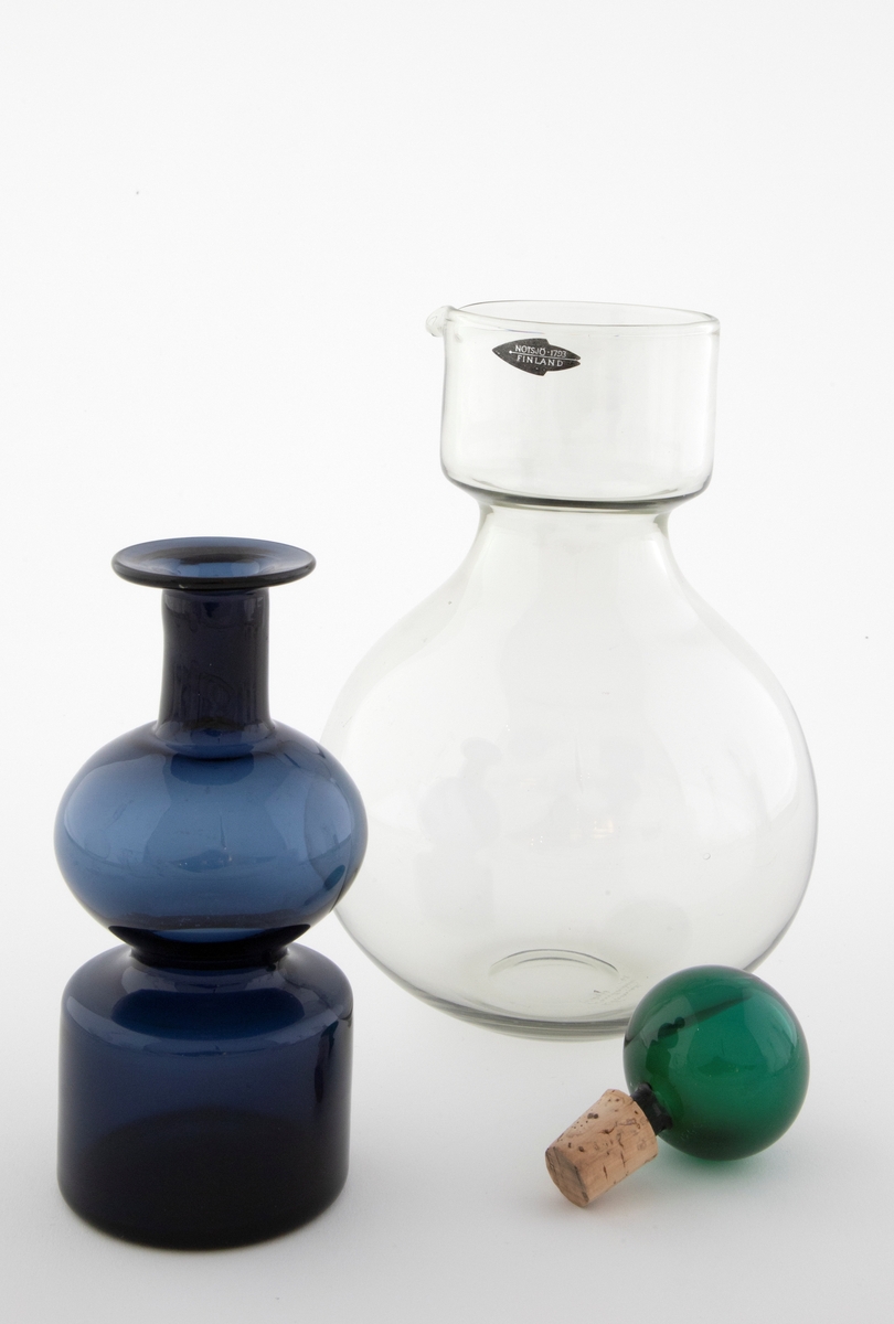Tredelt karaffel i klart glass: 

1) Stor kuleformet karaffel med hals i klart glass. Sylindrisk hals med tut.
 
2) Mindre karaffel i gjennomskinnelig, blått glass, plassert som propp i den store. Den har kuleformet korpus og sylindrisk hals, og hviler på en sylindrisk fot. 

3) Kuleformet propp plassert i den lille karaffelen, utført i gjennomskinnelig grønt glass og hviler på en korkring.
