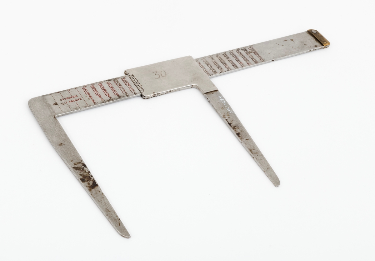 Skyveklave for diameter- og prisberegning av tømmer, altså en såkalt «prisklave». Redskapet er lagd av rustfritt stål. Klaven har en 40,5 centimeter lang, rett linjal med rektangulært tverrsnitt (3,6 X 0,3 centimeter). I den ene enden er det en rettvinklet 17,5 centimeter lang klavearm (målt langs innersida, 21,3 centimeter utvendig) som smalner noe mot ytterenden. Klaven har også en bevegelig arm med samme lengde og samme vinkling i forhold til linjalaksen. Denne armen er festet til en 8,9 centimeter lang fal, ei stålhylse, som omslutter klavelinjalen og tjente som handtak når den bevegelige klavearmen skulle posisjoneres under målingsarbeidet. Denne komponenten hindres fra å løsne ved hjelp av et påklinket messingbeslag i ytterenden av klavelinjalen. På begge sider av ståldekselet er tallene 6, 7, 8, 9, 10, 11, 12, 13, 14, 15 og 16 innstemplet. Disse tallene refererer antakelig til relevante lengdemål på tømmerstokker, oppgitt i halvmetere. Ved å sammenholde disse tallene med tallrekker på klavelinjalens plansider kunne man lese grunnprisinformasjon i hele kronebeløp. Over den ene av disse tabellene, mot linjalkanten, finner vi også ei tallrekke som gjorde det mulig å lese av stokkdiametere mellom 8 og 35 centimeter. Den ytre delen av linjalen er stempelmerket «BJØRNRUD & ARNESTAD  OSLO  RUSTFRITT STÅL  6-16». På den ene sida av stålfalen for den bevegelige klavearmen har noen risset inn tallet «30». Dette kan ha vært et nummer som refererte til Sønsterud skogskoles lister over materiell som ble stilt til elevenes disposisjon i forbindelse med praksisundervisninga.