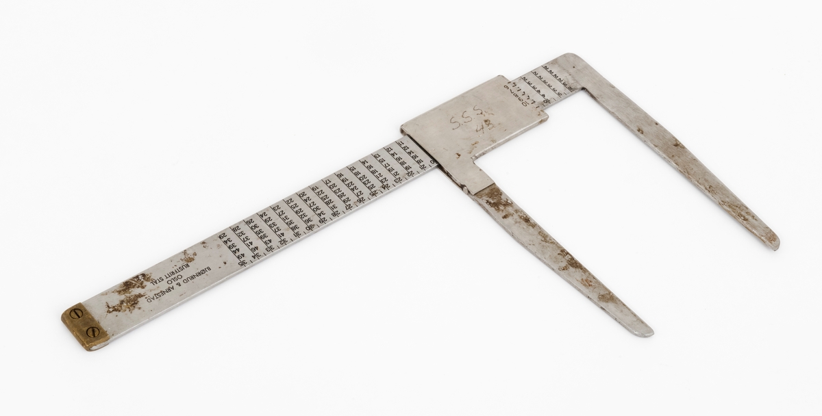 Skyveklave for diameter- og prisberegning av tømmer, altså en såkalt «prisklave». Redskapet er lagd av rustfritt stål. Klaven har en 40,5 centimeter lang, rett linjal med rektangulært tverrsnitt (3,1 X 0,3 centimeter). I den ene enden er det en rettvinklet 17,5 centimeter lang klavearm (målt langs innersida, 20,7 centimeter utvendig) som smalner noe mot ytterenden. Klaven har også en bevegelig arm med samme lengde og samme vinkling i forhold til linjalaksen. Denne armen er festet til en 9,0 centimeter lang fal, ei stålhylse, som omslutter klavelinjalen og tjente som handtak når den bevegelige klavearmen skulle posisjoneres under målingsarbeidet. Denne komponenten hindres fra å løsne ved hjelp av et påklinket messingbeslag i ytterenden av klavelinjalen. På den ene sida av stålhylsa, ved kanten, er tallene 6, 7, 8, 9 innstemplet, på den andre sida fortsetter tallrekka med 11, 12, 13, 14, 15 og 16. Disse sifrene refererer antakelig til relevante lengdemål på tømmerstokker, oppgitt i halvmetere. Ved å sammenholde disse tallene med tallrekker på klavelinjalens plansider kunne man lese grunnprisinformasjon i hele kronebeløp. Over den ene av disse tabellene, mot linjalkanten, finner vi også ei tallrekke som gjorde det mulig å lese av stokkdiametere mellom 8 og 35 centimeter. Den ytre delen av linjalen er stempelmerket «BJØRNRUD & ARNESTAD  OSLO  RUSTFRITT STÅL  6-16». På den ene sida av stålfalen for den bevegelige klavearmen har noen risset inn bokstav- og tallkonstellasjonen «S.S.S. 48». Bokstavene er nok en forkortelse for Statens skogskole Sønsterud. Tallene kan ha vært et nummer som refererte til skogskoles lister over materiell som ble stilt til elevenes disposisjon i forbindelse med praksisundervisninga.