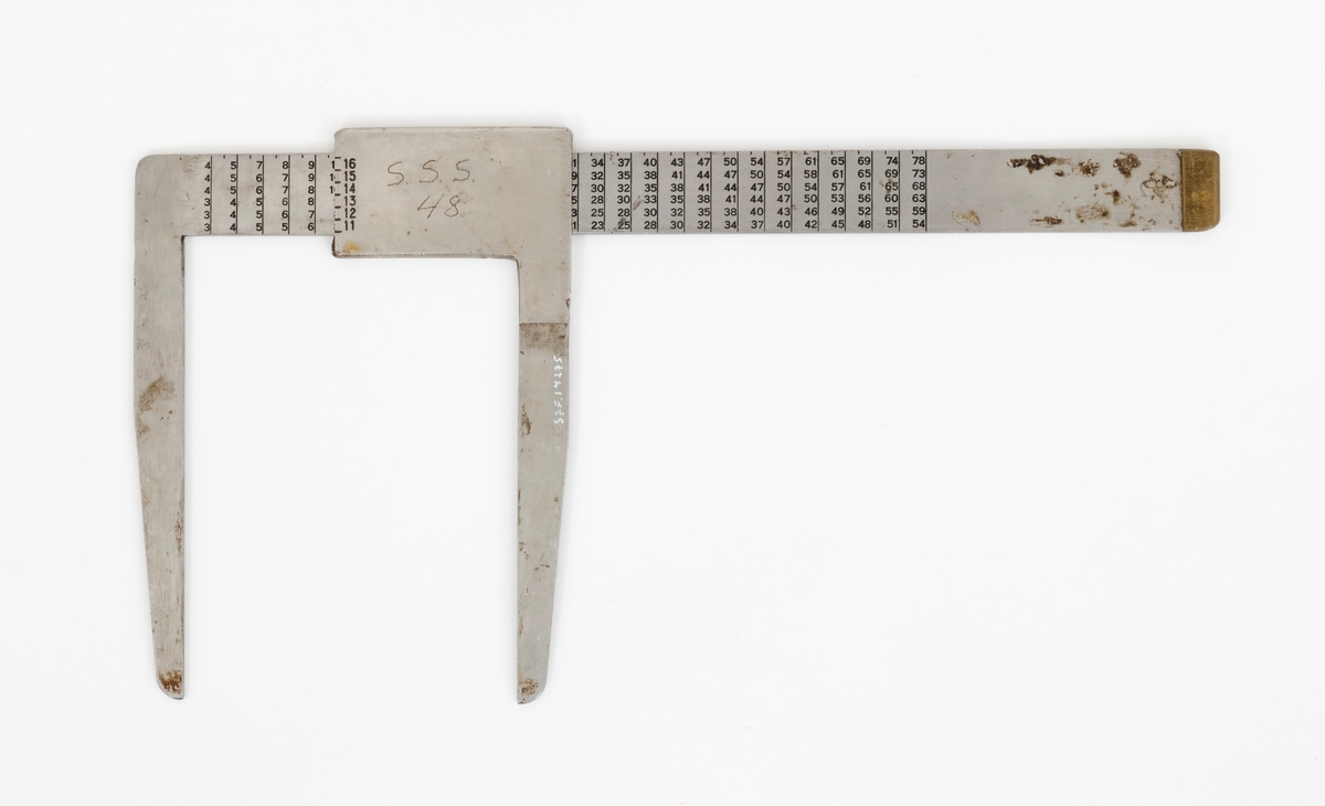 Skyveklave for diameter- og prisberegning av tømmer, altså en såkalt «prisklave». Redskapet er lagd av rustfritt stål. Klaven har en 40,5 centimeter lang, rett linjal med rektangulært tverrsnitt (3,1 X 0,3 centimeter). I den ene enden er det en rettvinklet 17,5 centimeter lang klavearm (målt langs innersida, 20,7 centimeter utvendig) som smalner noe mot ytterenden. Klaven har også en bevegelig arm med samme lengde og samme vinkling i forhold til linjalaksen. Denne armen er festet til en 9,0 centimeter lang fal, ei stålhylse, som omslutter klavelinjalen og tjente som handtak når den bevegelige klavearmen skulle posisjoneres under målingsarbeidet. Denne komponenten hindres fra å løsne ved hjelp av et påklinket messingbeslag i ytterenden av klavelinjalen. På den ene sida av stålhylsa, ved kanten, er tallene 6, 7, 8, 9 innstemplet, på den andre sida fortsetter tallrekka med 11, 12, 13, 14, 15 og 16. Disse sifrene refererer antakelig til relevante lengdemål på tømmerstokker, oppgitt i halvmetere. Ved å sammenholde disse tallene med tallrekker på klavelinjalens plansider kunne man lese grunnprisinformasjon i hele kronebeløp. Over den ene av disse tabellene, mot linjalkanten, finner vi også ei tallrekke som gjorde det mulig å lese av stokkdiametere mellom 8 og 35 centimeter. Den ytre delen av linjalen er stempelmerket «BJØRNRUD & ARNESTAD  OSLO  RUSTFRITT STÅL  6-16». På den ene sida av stålfalen for den bevegelige klavearmen har noen risset inn bokstav- og tallkonstellasjonen «S.S.S. 48». Bokstavene er nok en forkortelse for Statens skogskole Sønsterud. Tallene kan ha vært et nummer som refererte til skogskoles lister over materiell som ble stilt til elevenes disposisjon i forbindelse med praksisundervisninga.