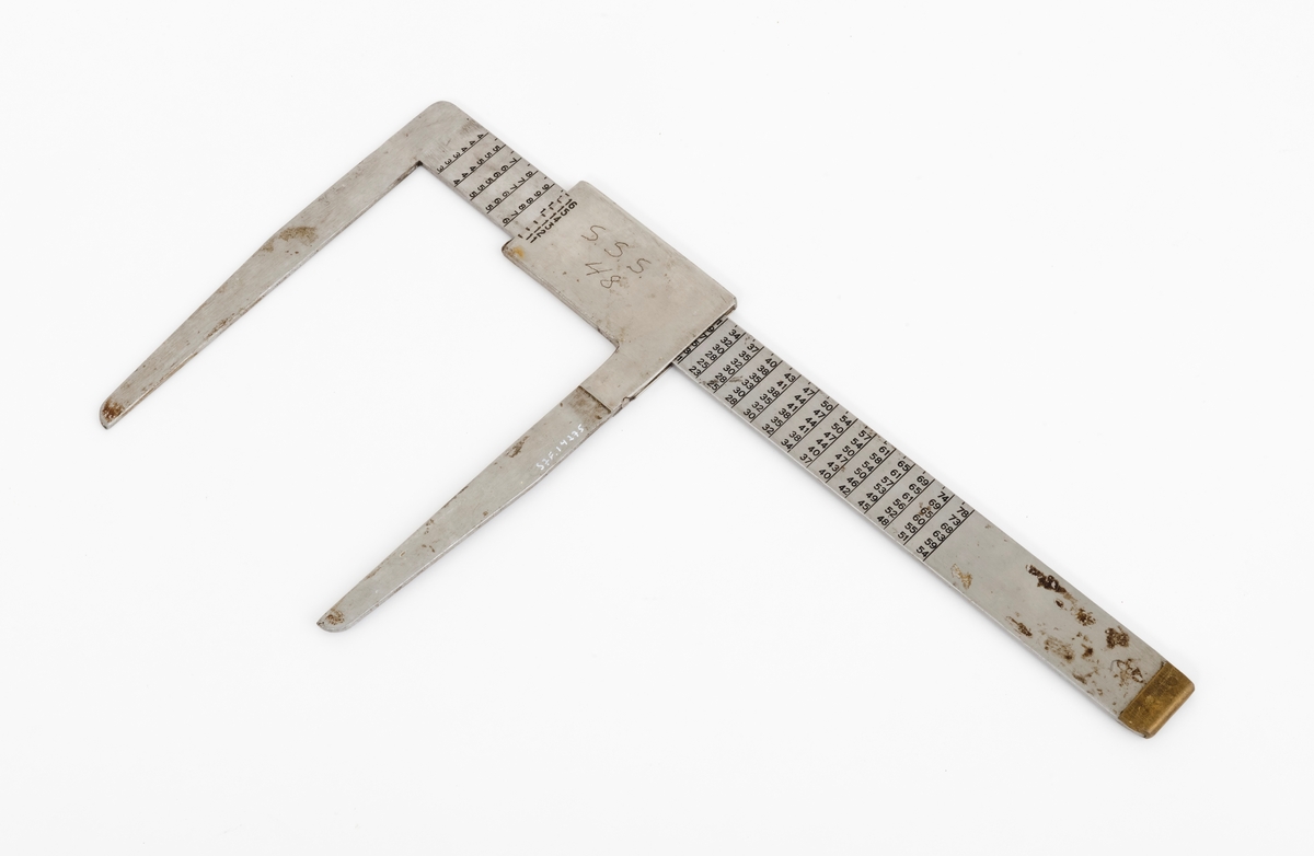 Skyveklave for diameter- og prisberegning av tømmer, altså en såkalt «prisklave». Redskapet er lagd av rustfritt stål. Klaven har en 40,5 centimeter lang, rett linjal med rektangulært tverrsnitt (3,1 X 0,3 centimeter). I den ene enden er det en rettvinklet 17,5 centimeter lang klavearm (målt langs innersida, 20,7 centimeter utvendig) som smalner noe mot ytterenden. Klaven har også en bevegelig arm med samme lengde og samme vinkling i forhold til linjalaksen. Denne armen er festet til en 9,0 centimeter lang fal, ei stålhylse, som omslutter klavelinjalen og tjente som handtak når den bevegelige klavearmen skulle posisjoneres under målingsarbeidet. Denne komponenten hindres fra å løsne ved hjelp av et påklinket messingbeslag i ytterenden av klavelinjalen. På den ene sida av stålhylsa, ved kanten, er tallene 6, 7, 8, 9 innstemplet, på den andre sida fortsetter tallrekka med 11, 12, 13, 14, 15 og 16. Disse sifrene refererer antakelig til relevante lengdemål på tømmerstokker, oppgitt i halvmetere. Ved å sammenholde disse tallene med tallrekker på klavelinjalens plansider kunne man lese grunnprisinformasjon i hele kronebeløp. Over den ene av disse tabellene, mot linjalkanten, finner vi også ei tallrekke som gjorde det mulig å lese av stokkdiametere mellom 8 og 35 centimeter. Den ytre delen av linjalen er stempelmerket «BJØRNRUD & ARNESTAD  OSLO  RUSTFRITT STÅL  6-16». På den ene sida av stålfalen for den bevegelige klavearmen har noen risset inn bokstav- og tallkonstellasjonen «S.S.S. 48». Bokstavene er nok en forkortelse for Statens skogskole Sønsterud. Tallene kan ha vært et nummer som refererte til skogskoles lister over materiell som ble stilt til elevenes disposisjon i forbindelse med praksisundervisninga.