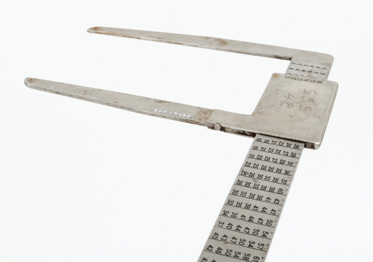 Skyveklave for diameter- og prisberegning av tømmer, altså en såkalt «prisklave». Redskapet er lagd av rustfritt stål. Klaven har en 40,5 centimeter lang, rett linjal med rektangulært tverrsnitt (3,1 X 0,3 centimeter). I den ene enden er det en rettvinklet 17,5 centimeter lang klavearm (målt langs innersida, 20,7 centimeter utvendig) som smalner noe mot ytterenden. Klaven har også en bevegelig arm med samme lengde og samme vinkling i forhold til linjalaksen. Denne armen er festet til en 9,0 centimeter lang fal, ei stålhylse, som omslutter klavelinjalen og tjente som handtak når den bevegelige klavearmen skulle posisjoneres under målingsarbeidet. Denne komponenten hindres fra å løsne ved hjelp av et påklinket messingbeslag i ytterenden av klavelinjalen. På den ene sida av stålhylsa, ved kanten, er tallene 6, 7, 8, 9 innstemplet, på den andre sida fortsetter tallrekka med 11, 12, 13, 14, 15 og 16. Disse sifrene refererer antakelig til relevante lengdemål på tømmerstokker, oppgitt i halvmetere. Ved å sammenholde disse tallene med tallrekker på klavelinjalens plansider kunne man lese grunnprisinformasjon i hele kronebeløp. Over den ene av disse tabellene, mot linjalkanten, finner vi også ei tallrekke som gjorde det mulig å lese av stokkdiametere mellom 8 og 35 centimeter. Den ytre delen av linjalen er stempelmerket «BJØRNRUD & ARNESTAD  OSLO  RUSTFRITT STÅL  6-16». På den ene sida av stålfalen for den bevegelige klavearmen har noen risset inn bokstav- og tallkonstellasjonen «S.S.S. 48». Bokstavene er nok en forkortelse for Statens skogskole Sønsterud. Tallene kan ha vært et nummer som refererte til skogskoles lister over materiell som ble stilt til elevenes disposisjon i forbindelse med praksisundervisninga.