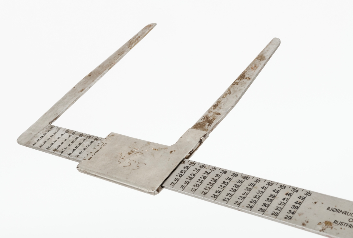 Skyveklave for diameter- og prisberegning av tømmer, altså en såkalt «prisklave». Redskapet er lagd av rustfritt stål. Klaven har en 40,5 centimeter lang, rett linjal med rektangulært tverrsnitt (3,1 X 0,3 centimeter). I den ene enden er det en rettvinklet 17,5 centimeter lang klavearm (målt langs innersida, 20,7 centimeter utvendig) som smalner noe mot ytterenden. Klaven har også en bevegelig arm med samme lengde og samme vinkling i forhold til linjalaksen. Denne armen er festet til en 9,0 centimeter lang fal, ei stålhylse, som omslutter klavelinjalen og tjente som handtak når den bevegelige klavearmen skulle posisjoneres under målingsarbeidet. Denne komponenten hindres fra å løsne ved hjelp av et påklinket messingbeslag i ytterenden av klavelinjalen. På den ene sida av stålhylsa, ved kanten, er tallene 6, 7, 8, 9 innstemplet, på den andre sida fortsetter tallrekka med 11, 12, 13, 14, 15 og 16. Disse sifrene refererer antakelig til relevante lengdemål på tømmerstokker, oppgitt i halvmetere. Ved å sammenholde disse tallene med tallrekker på klavelinjalens plansider kunne man lese grunnprisinformasjon i hele kronebeløp. Over den ene av disse tabellene, mot linjalkanten, finner vi også ei tallrekke som gjorde det mulig å lese av stokkdiametere mellom 8 og 35 centimeter. Den ytre delen av linjalen er stempelmerket «BJØRNRUD & ARNESTAD  OSLO  RUSTFRITT STÅL  6-16». På den ene sida av stålfalen for den bevegelige klavearmen har noen risset inn bokstav- og tallkonstellasjonen «S.S.S. 48». Bokstavene er nok en forkortelse for Statens skogskole Sønsterud. Tallene kan ha vært et nummer som refererte til skogskoles lister over materiell som ble stilt til elevenes disposisjon i forbindelse med praksisundervisninga.