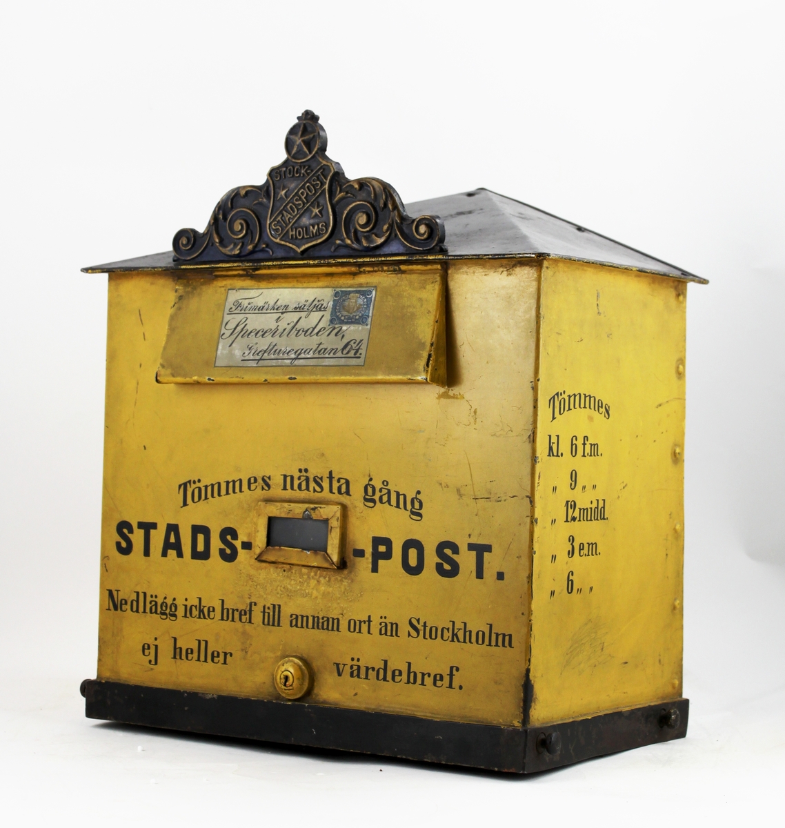 Brevlåda med sluttande, brutet tak. I främre delen av taket ett av Stockholms stadspost emblem. Brevlådans tak och ramen runt brevlådans botten är svart i övrigt är brevlådan gul. På inläggsklaffen ett vitt kuvert med ett av Stadspostens frimärken och texten "Frimärken säljas i Speceriboden Grefturegatan 64".
Där under en liten glasruta avsedd för visning av tömningstider. Brevlådans front har inskription. Brevlådan tömmes från botten med en tömningsväska. Ett lås är centrerat i lådans nederkant. Nyckeln har PM 1642.