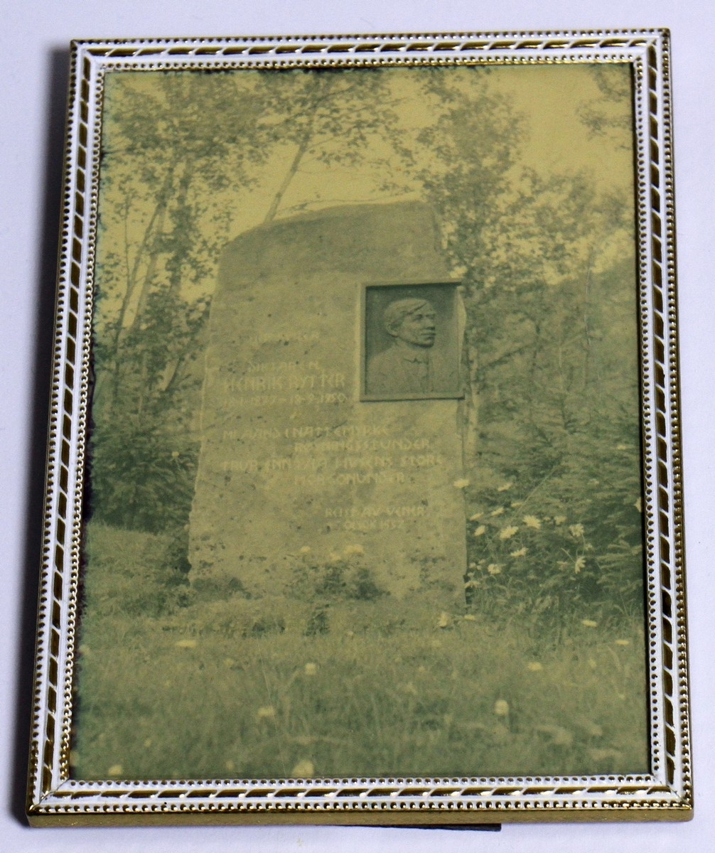 Fotografi av Bautasteinen på "Rytterhaugen" ved den innvigde urneplassen. Fotografiet kjem frå 1962. Det står vidare: "Jonsok 1952 vart bautaen reist av bygdefolket i Ustedalen og på Geilo, og andre vener. Dei siste linene Henrik Rytter skreiv, er hogd inn på bautaen: Og likevel ja, likevel mi ånd i nattemyrke røyningsstunder trur enn på livsens store morgonunder". Vedlagt fotografiet følgjer ei informasjonstekst. Både foto og tekst er i glas og ramme. Biletet av bautaen har måla 12,2 x 17,2 cm, medan teksten har måla 18 x 18 cm.