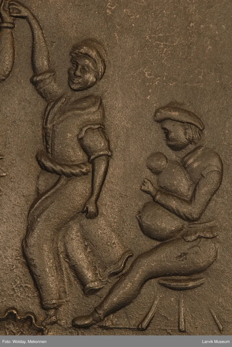 dansende bønder til høyre spillemann med sekkepipe sittende i profil mot venstre på lav krakk til venstre vassele og to trebøtter.