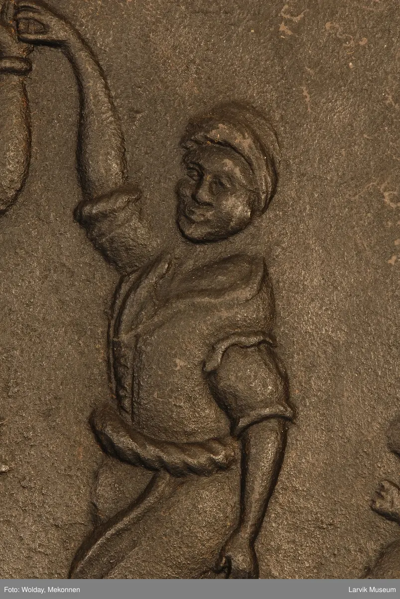 dansende bønder til høyre spillemann med sekkepipe sittende i profil mot venstre på lav krakk til venstre vassele og to trebøtter.