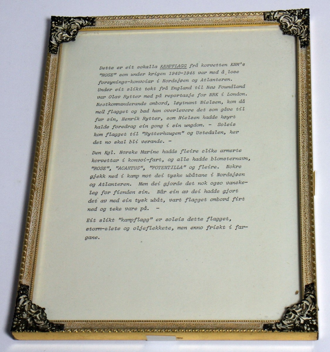 Norsk skipsflagg frå den andre verdskrigen, som vart gjeve i gåve til diktaren Henrik Rytter frå offiserar og mannskap på korvetten H.Nor MS "Rose". Marineskipet "Rose" forliste 26. oktober 1944 etter ein kollisjon med den britiske fregatten Manners. (1) Henrik Rytter var i tysk fangenskap under krigen. 

I den innramma følgjeteksten står det følgjande: "Dette er eit sokalla KAMPFLAGG frå korvetten KNM's "ROSE" som under krigen 1940-1945 var med å lose forsynings-konvoiar i Nordsjøen og Atlanteren. Under eit slikt tokt frå England til New Foundland var Olav Rytter med på reportasje for NRK i London. Nestkommanderande ombord, løytnant Nielsen, kom då med flagget og bad han overlevere det som gåve til far sin, Henrik Rytter, som Nielsen hadde høyrt halde foredrag ein gong i sin ungdom. - Soleis kom flagget til "Rytterhaugen" og Ustedalen, her det no skal bli verande. - 

Den Kgl. Norske Marine hadde fleire slike armerte korvettar i konvoi-fart, og alle hadde blomsternavn, "Rose", "Acantus", "Potentilla" og fleire. Nokre gjekk ned i kamp mot dei tyske ubåtane i Nordsjøen og Atlanteren. Men dei gjorde det nok ogso vanskeleg for fienden sin. Når ein av dei hadde gjort det av med ein tysk ubåt, vart flagget ombord firt ned og teke vare på. -

Eit slikt "kampflagg" er soleis dette flagget, storm-slete og oljeflekkete, men enno friskt i fargane.

Kjelde:
https://www.sjohistorie.no/no/skip/24393/ (Lesedato: 08.12.2020)