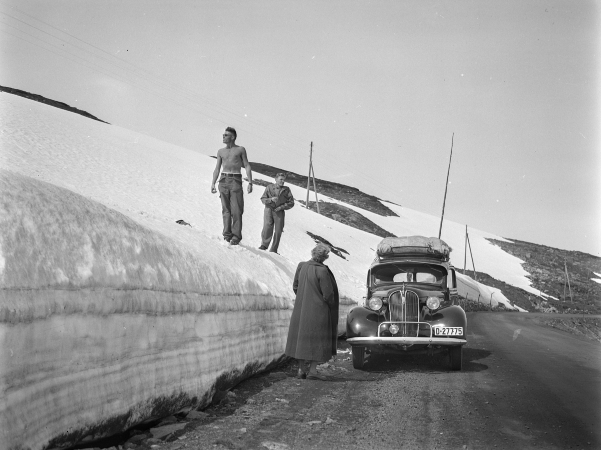 Skottefamilie på biltur over Strynefjell med bil D-27775. Magne og Hallvard på snøkanten og Ragnhild Skotte med ryggen til